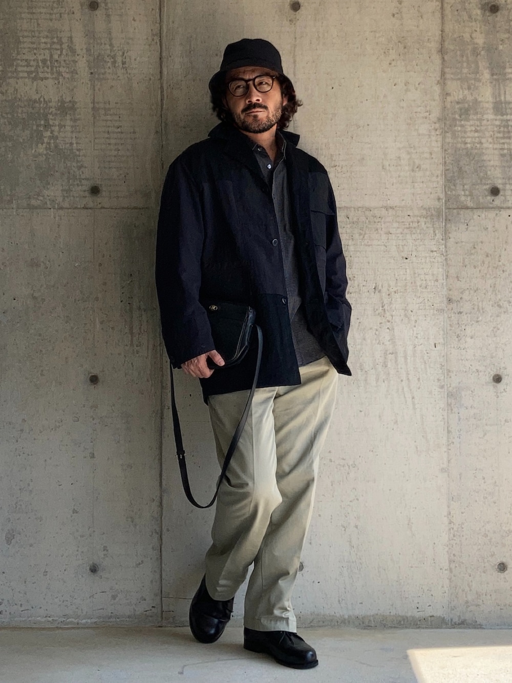 ブラック系のナイロンジャケット、ベージュ系のチノパンツ、ブラック系のその他シューズを着用したメンズの春コーディネートの2枚目の写真