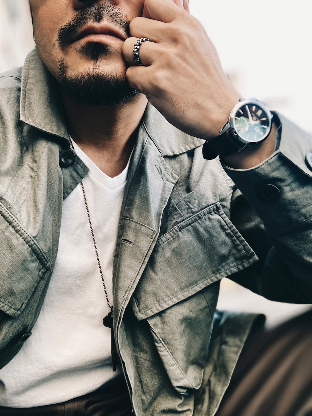 ホワイト系のTシャツ/カットソー、グリーン系のミリタリージャケット、グレー系のスラックスを着用したメンズの春コーディネートの5枚目の写真