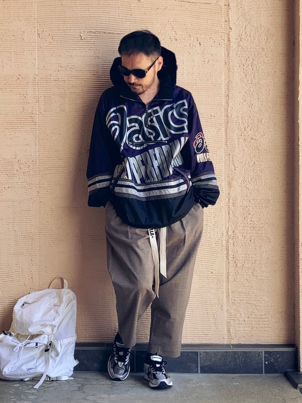 パープル系のナイロンジャケット、ブラウン系のスラックス、ブラック系のスニーカーを着用したメンズの秋コーディネートの2枚目の写真