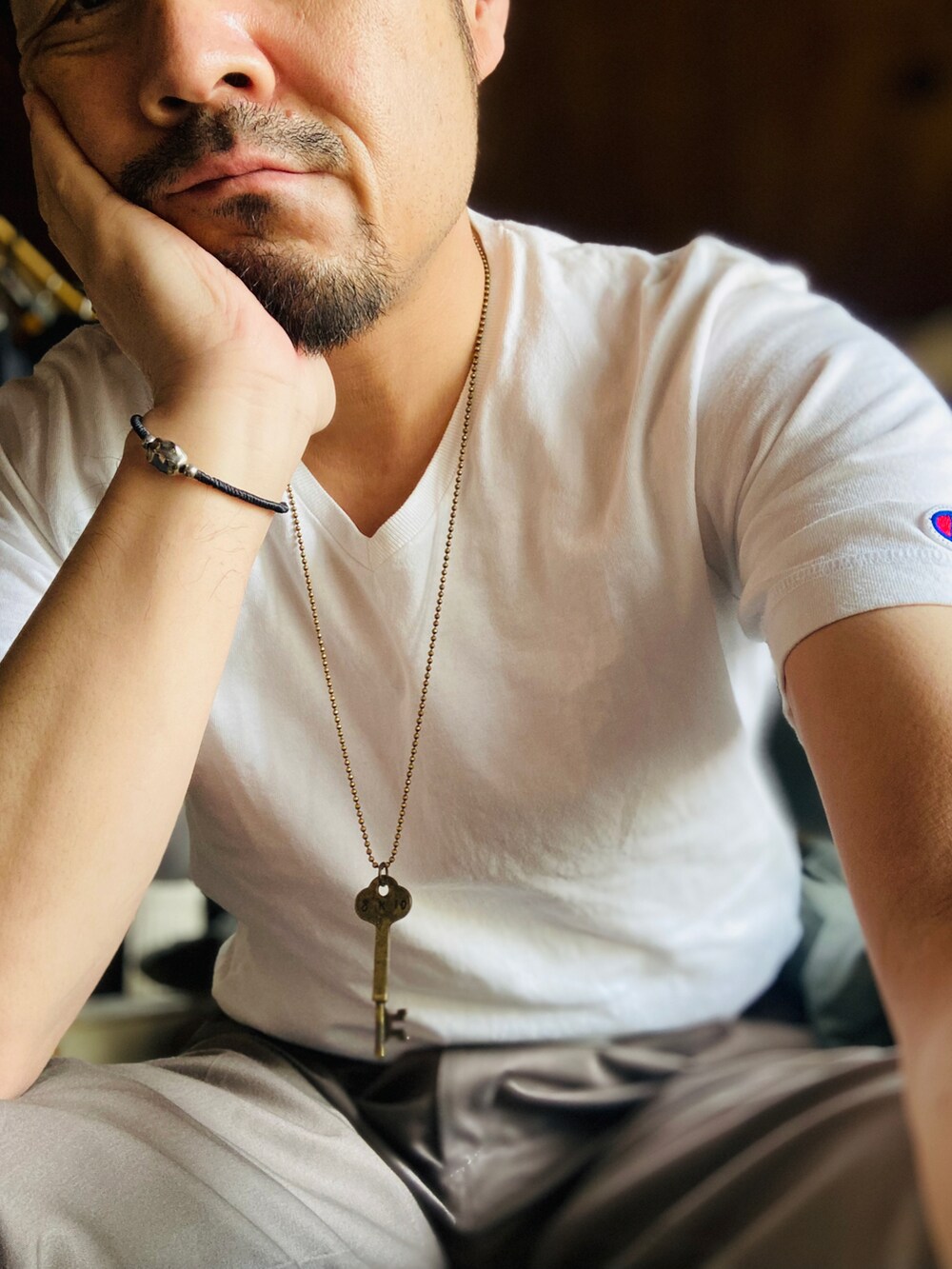 ホワイト系のTシャツ/カットソー、グレー系のスラックス、ブラウン系のローファーを着用したメンズの春コーディネートの3枚目の写真