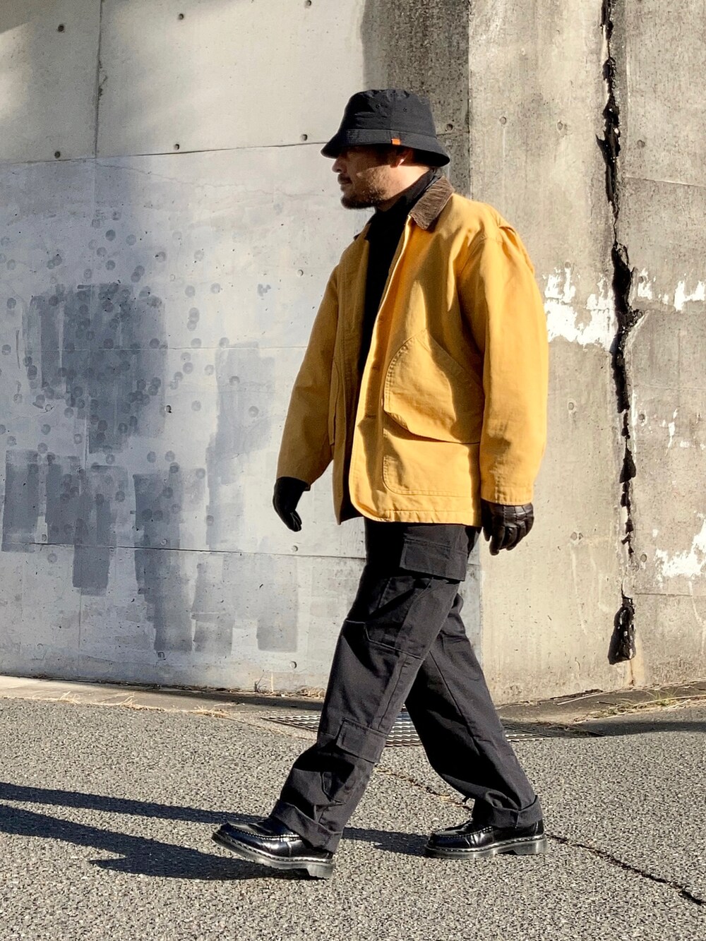 ブラック系のTシャツ/カットソー、ブルー系のデニムジャケット、イエロー系のカバーオールを着用したメンズの冬コーディネートの2枚目の写真