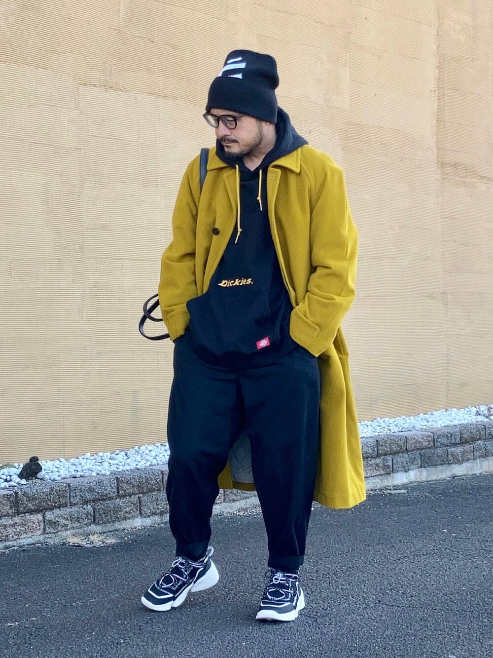 ブラック系のパーカー、イエロー系のステンカラーコート、ブラック系のその他パンツを着用したメンズの冬コーディネートの2枚目の写真