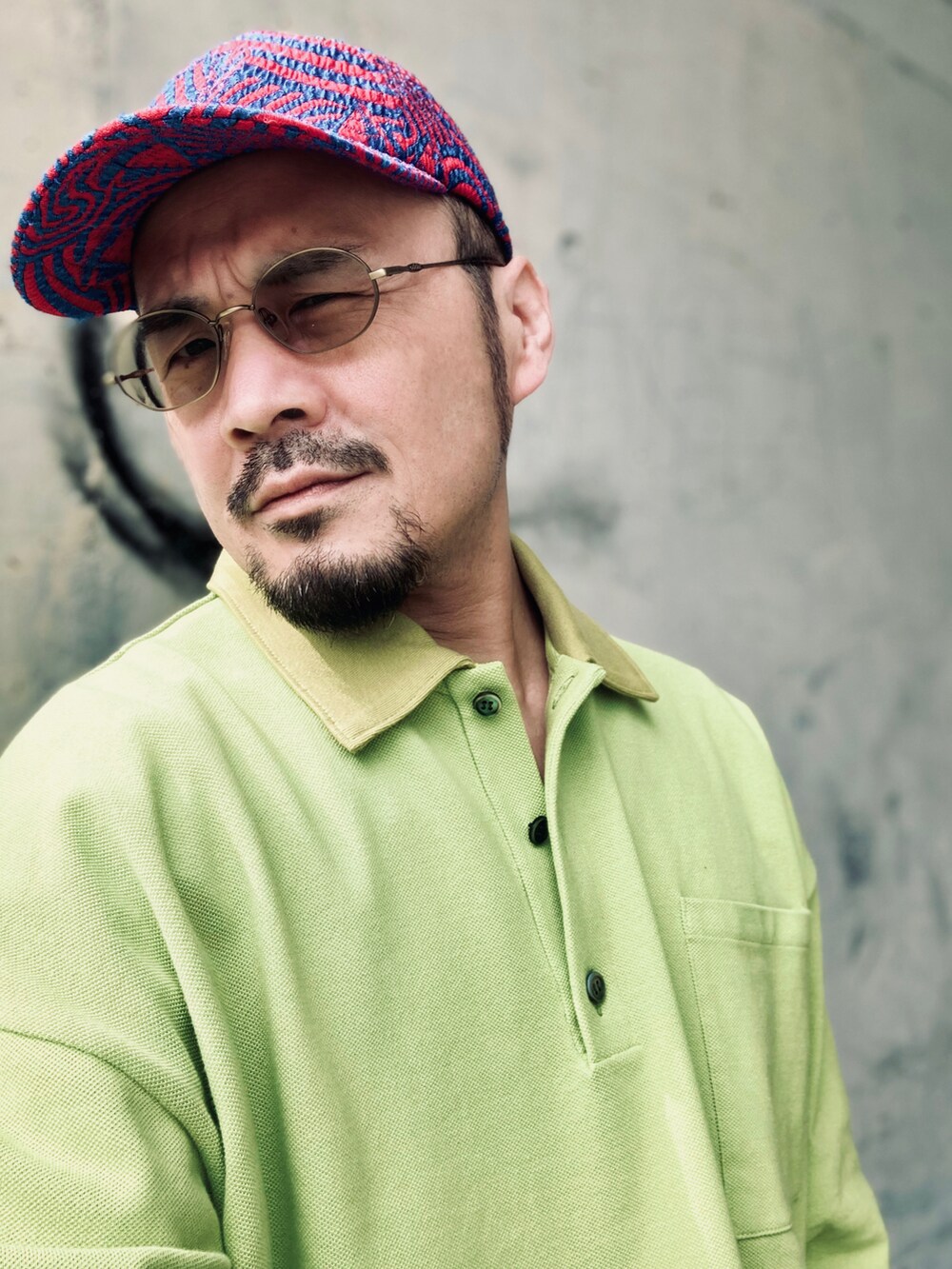 グリーン系のポロシャツ、ブルー系のデニムパンツ、ブラック系のスニーカーを着用したメンズの春コーディネートの4枚目の写真