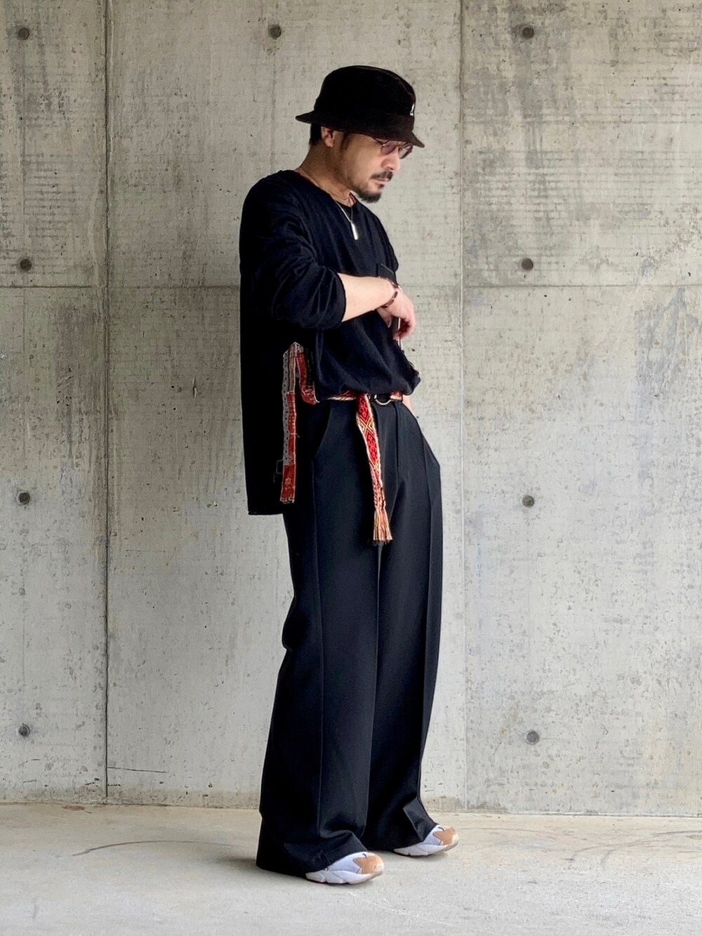 ブラック系のTシャツ/カットソー、ブラック系のスラックス、レッド系のスニーカーを着用したメンズの春コーディネートの2枚目の写真