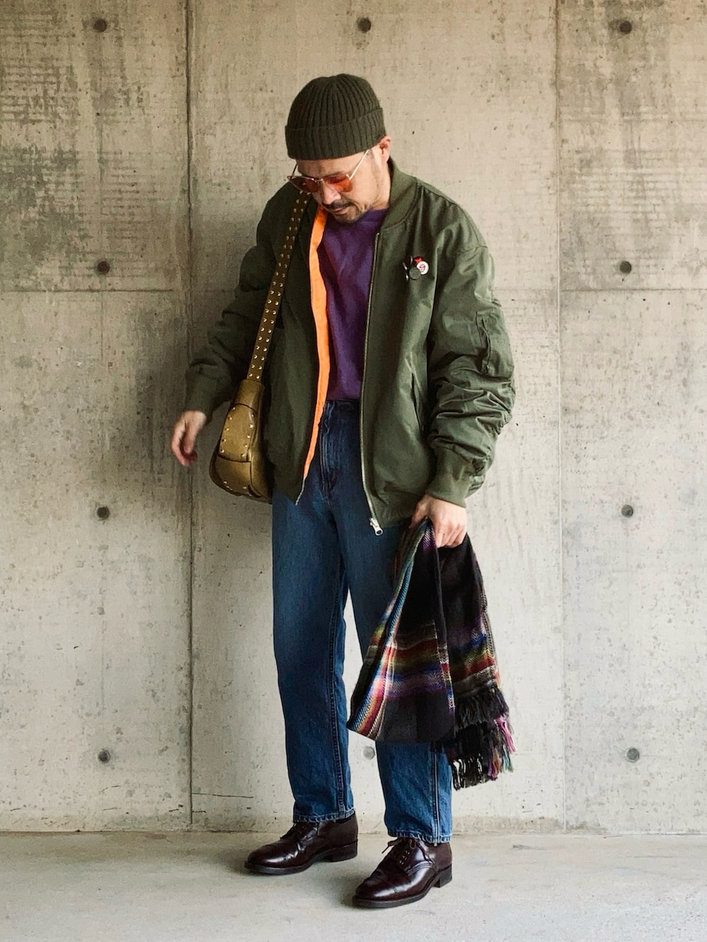 パープル系のスウェット、グリーン系のMA-1、ブルー系のデニムパンツを着用したメンズの冬コーディネートの2枚目の写真