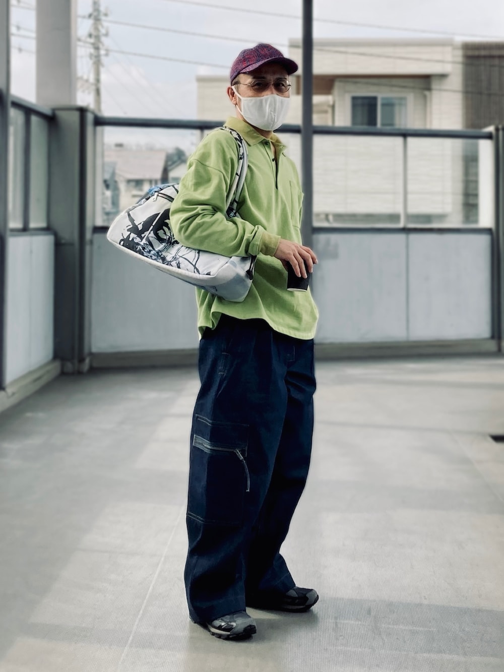 グリーン系のポロシャツ、ブルー系のデニムパンツ、ブラック系のスニーカーを着用したメンズの春コーディネートの5枚目の写真