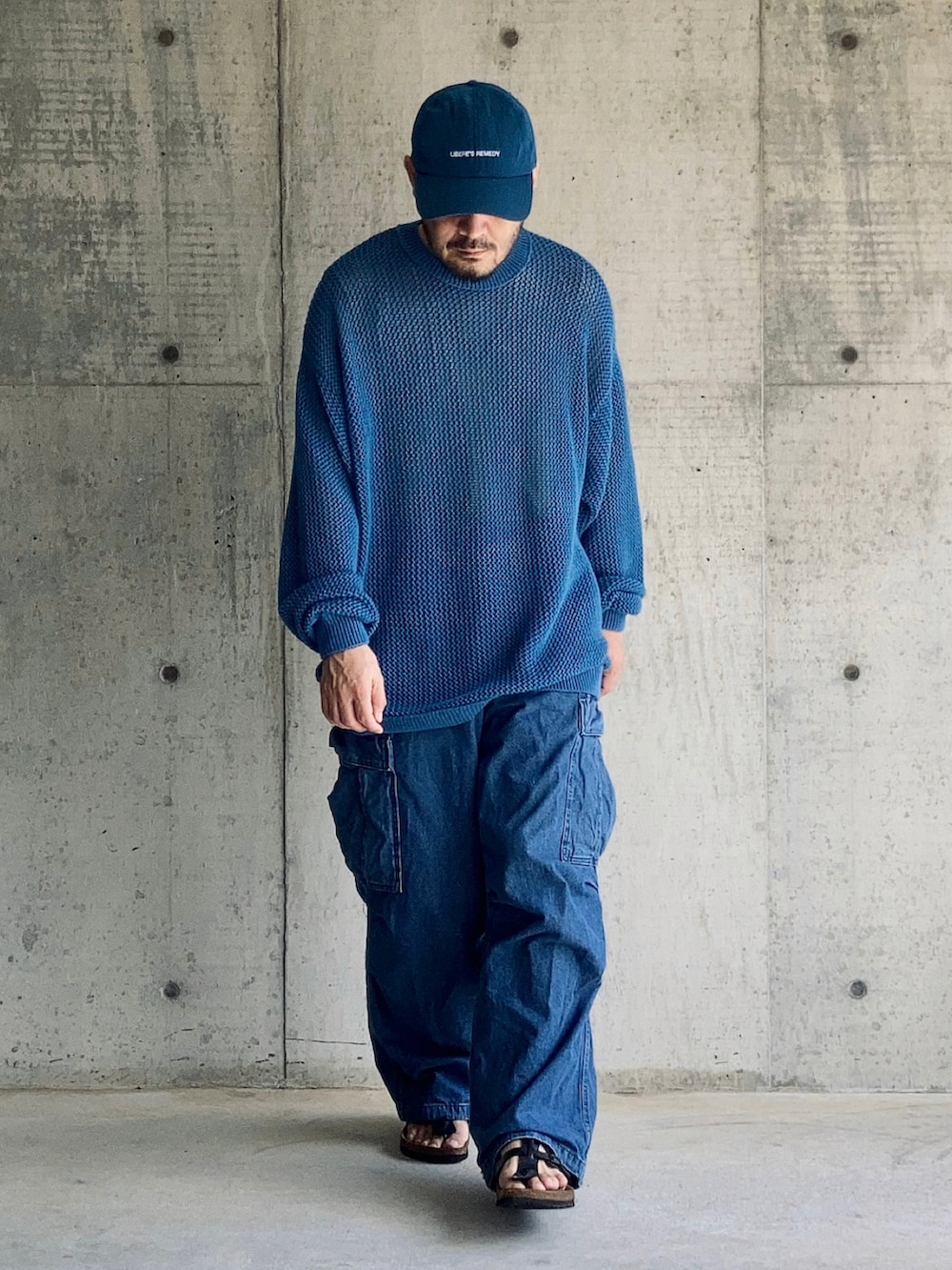 ブルー系のニット/セーター、ブルー系のカーゴパンツ、ブラック系のサンダルを着用したメンズの秋コーディネートの4枚目の写真