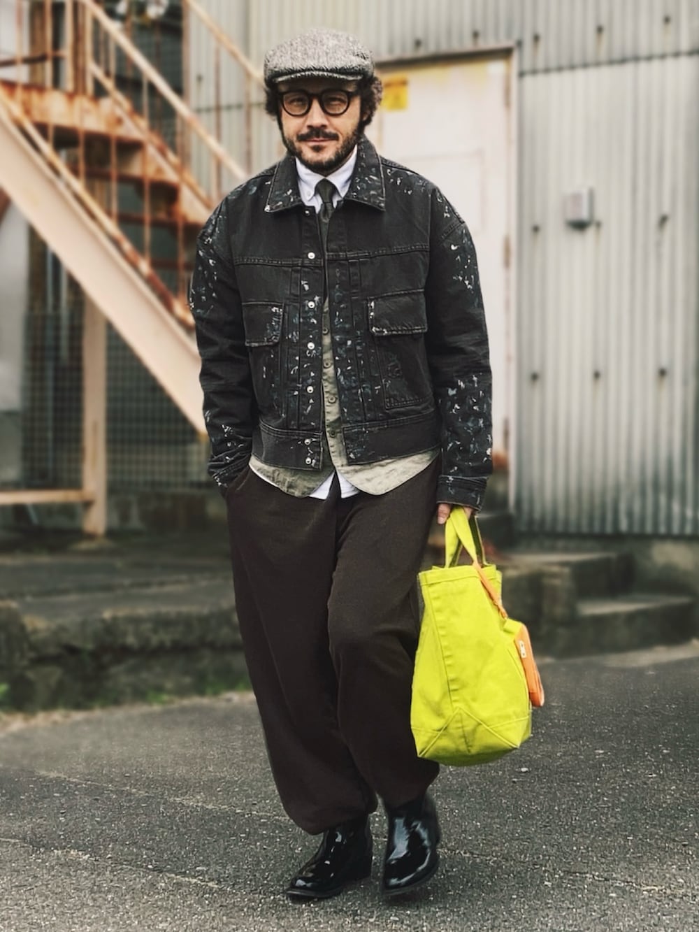 ブラウン系のデニムジャケット、グリーン系のベスト、ブラウン系のスウェットパンツを着用したメンズの春コーディネートの2枚目の写真