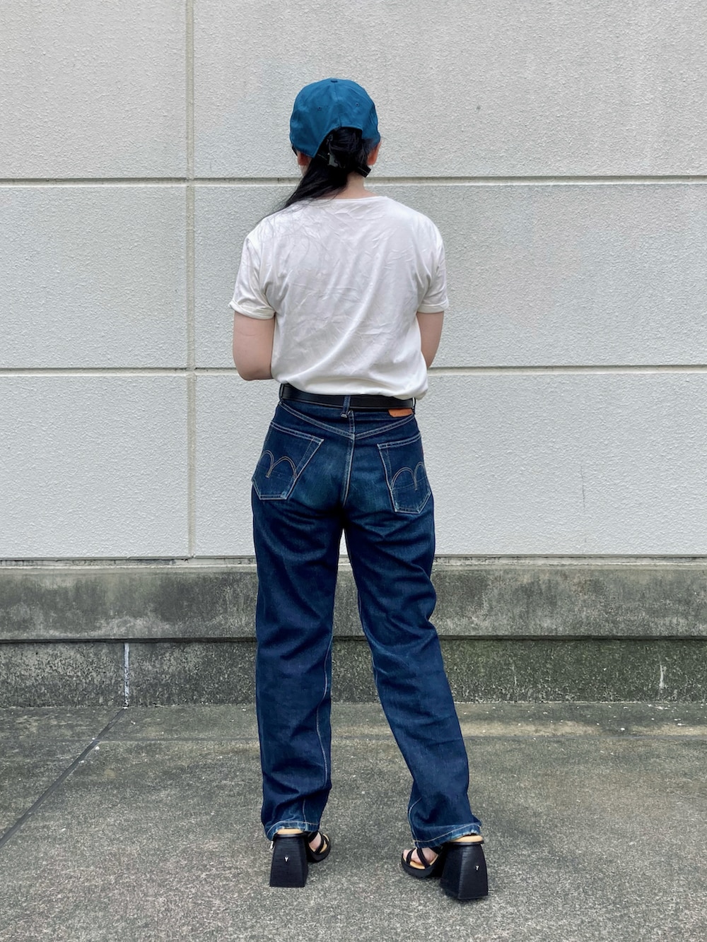 ブルー系のデニムパンツ、ブラック系のサンダル、ブラック系のベルトを着用したレディースの夏コーディネートの2枚目の写真