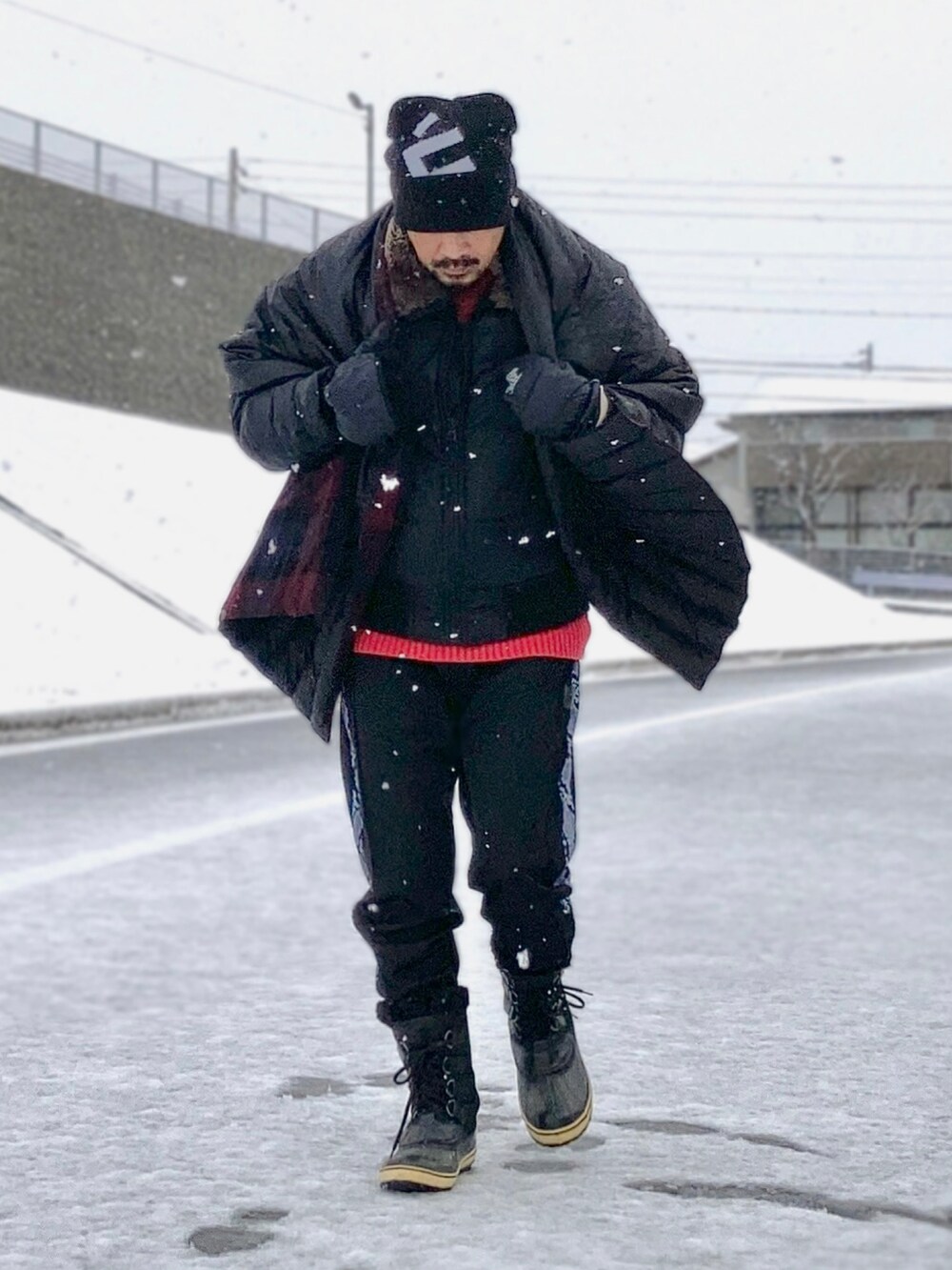 ベージュ系のTシャツ/カットソー、レッド系のニット/セーター、ブラック系のダウンジャケット/コートを着用したメンズの冬コーディネートの3枚目の写真