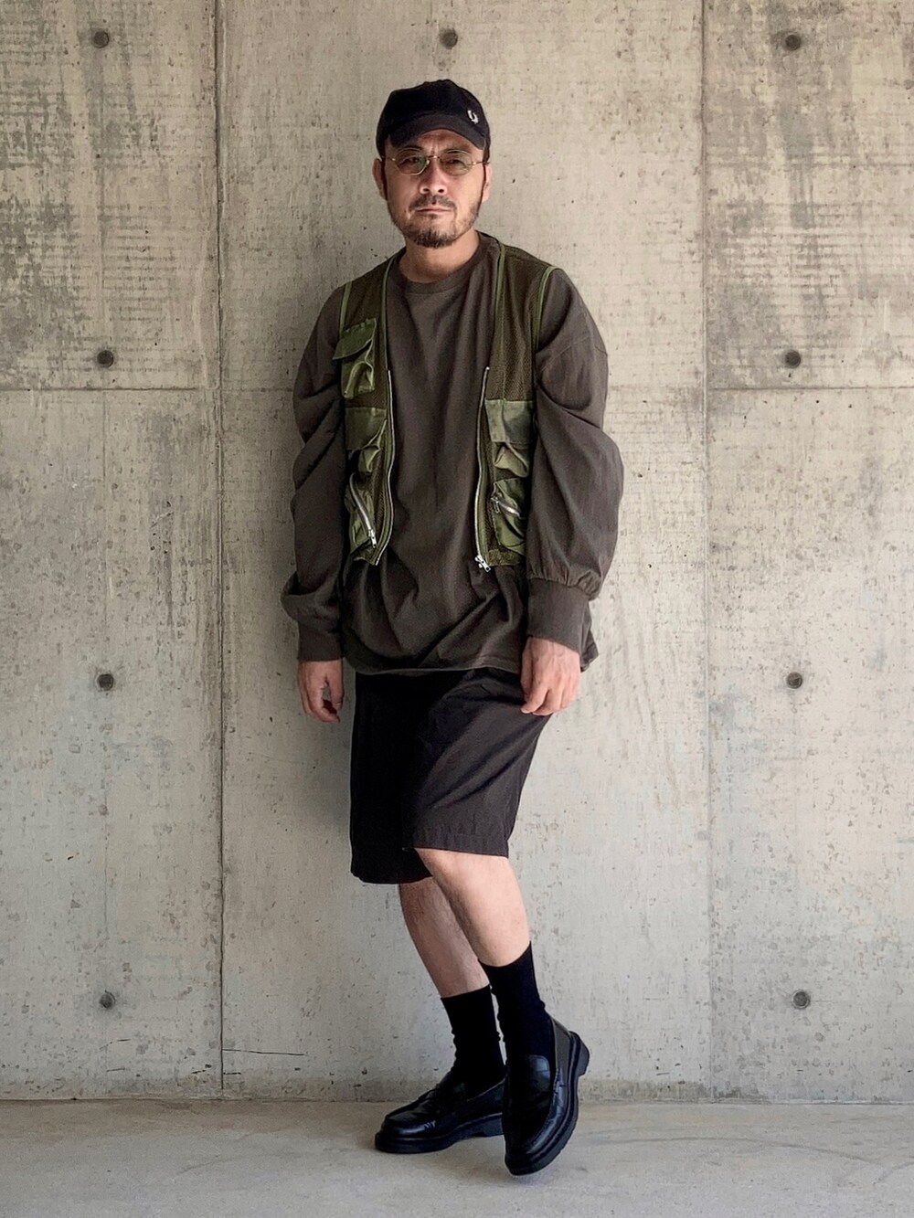 グリーン系のTシャツ/カットソー、グリーン系のベスト、ブラウン系のパンツを着用したメンズの秋コーディネートの2枚目の写真