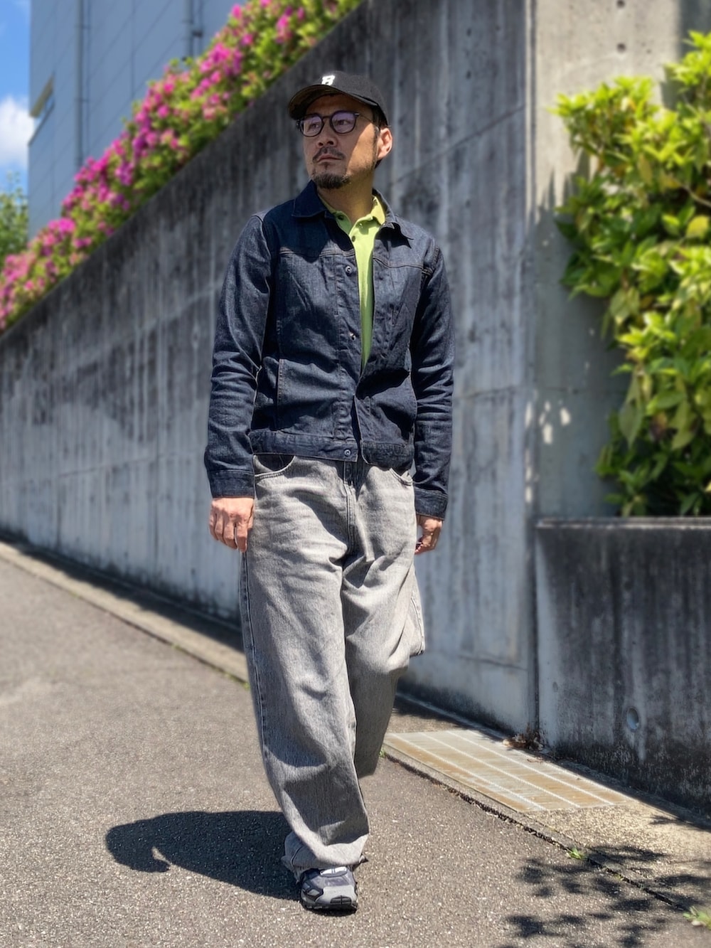グリーン系のポロシャツ、ブルー系のデニムジャケット、グレー系のデニムパンツを着用したメンズの春コーディネートの2枚目の写真