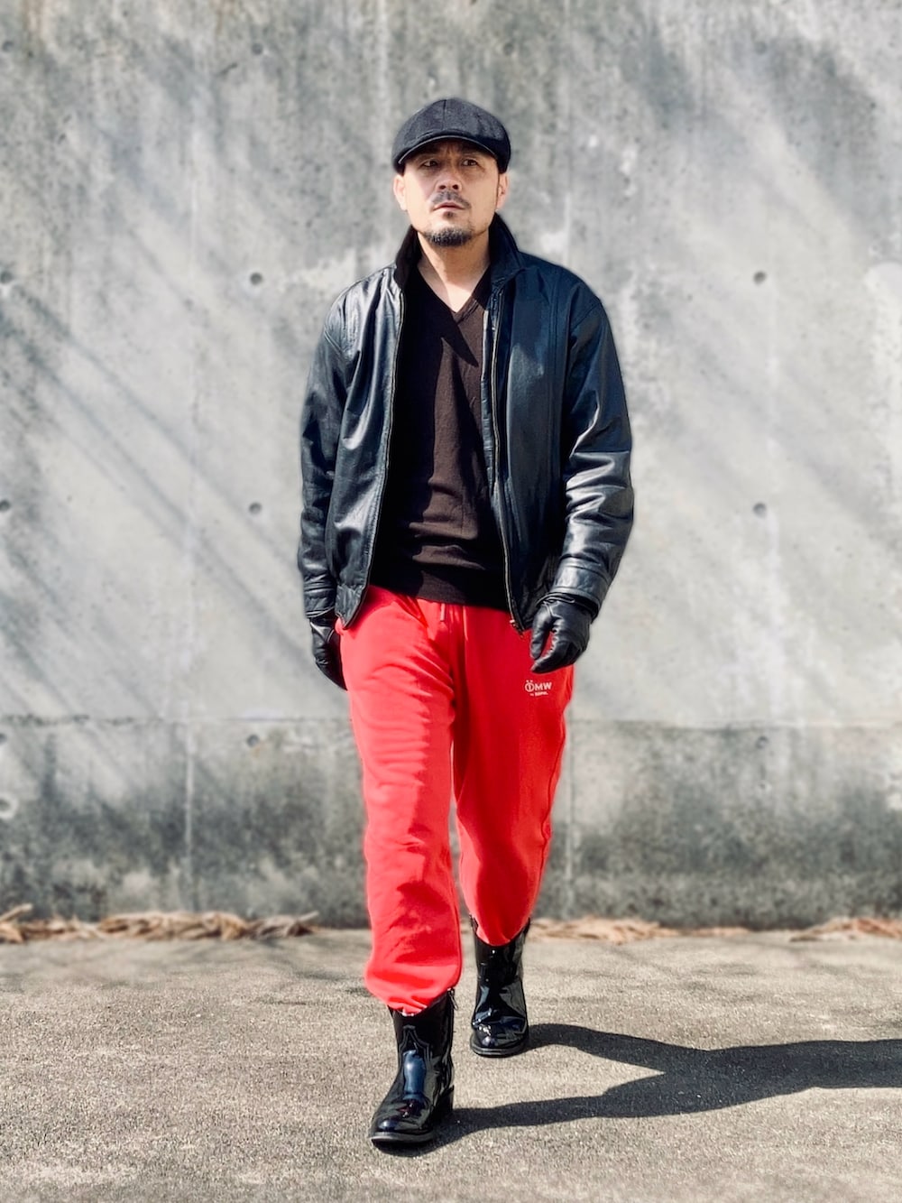 レッド系のスウェットパンツ、ブラック系のブルゾン、ブラック系のブーツを着用したメンズの春コーディネートの3枚目の写真