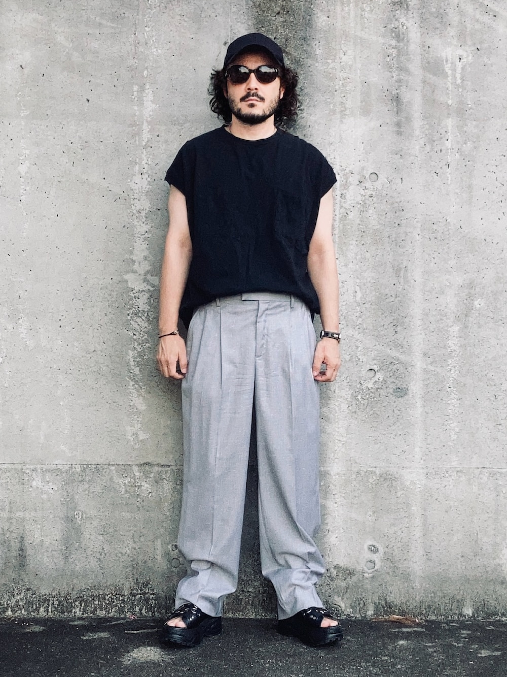 グレー系のスラックス、ブラック系のその他トップス、ブラック系のサンダルを着用したメンズの夏コーディネートの2枚目の写真