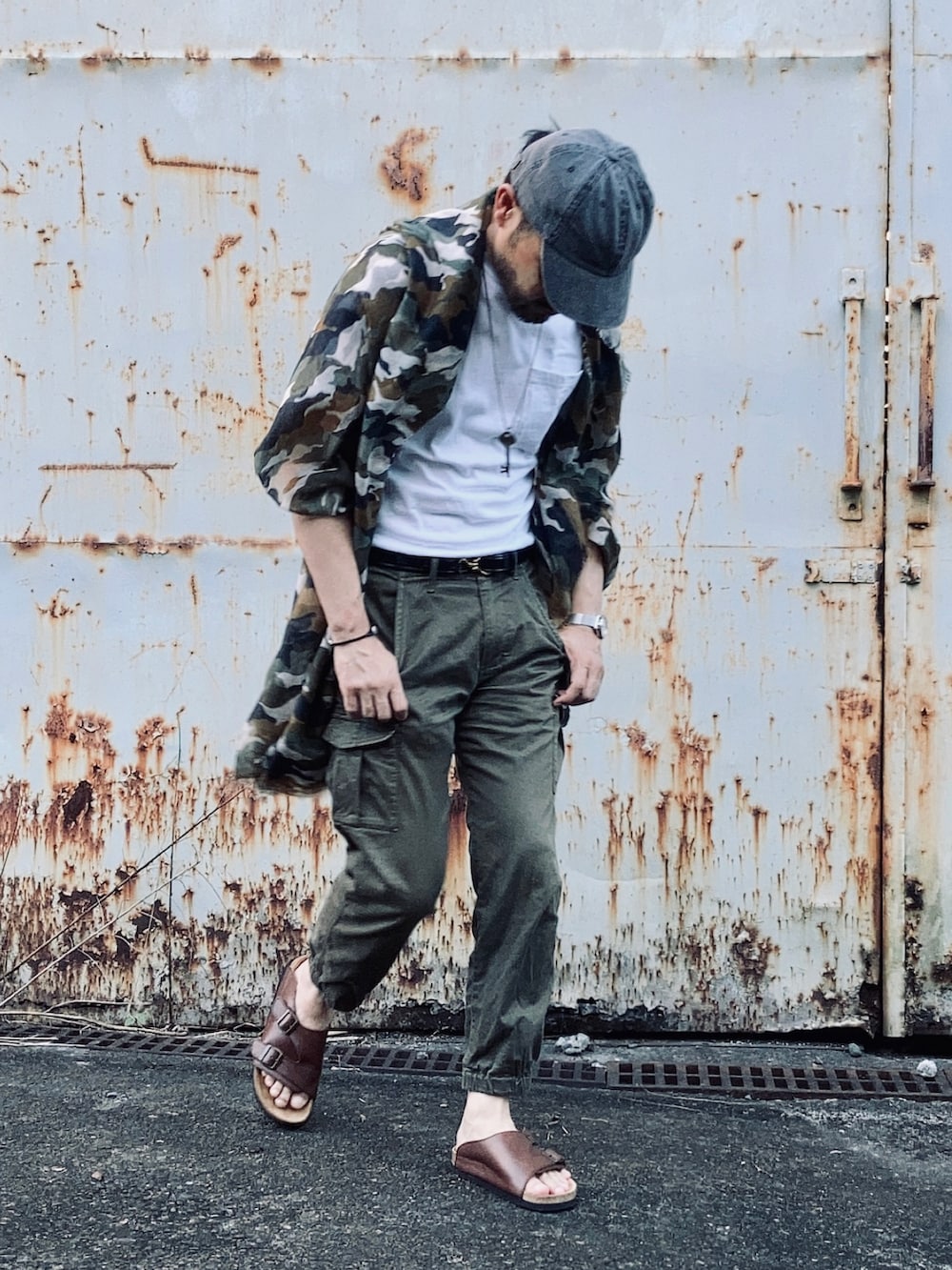 ホワイト系のTシャツ/カットソー、グリーン系のパンツ、ブラウン系のサンダルを着用したメンズの夏コーディネートの3枚目の写真