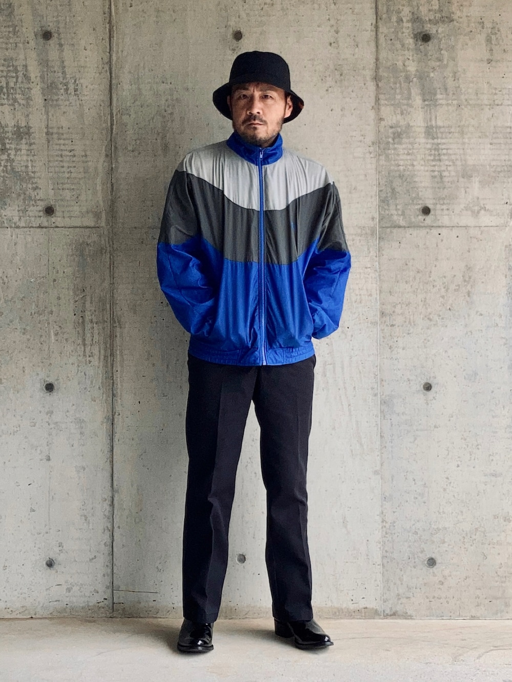 ブルー系のナイロンジャケット、ブルー系のチノパンツ、ブラック系のブーツを着用したメンズの秋コーディネートの2枚目の写真