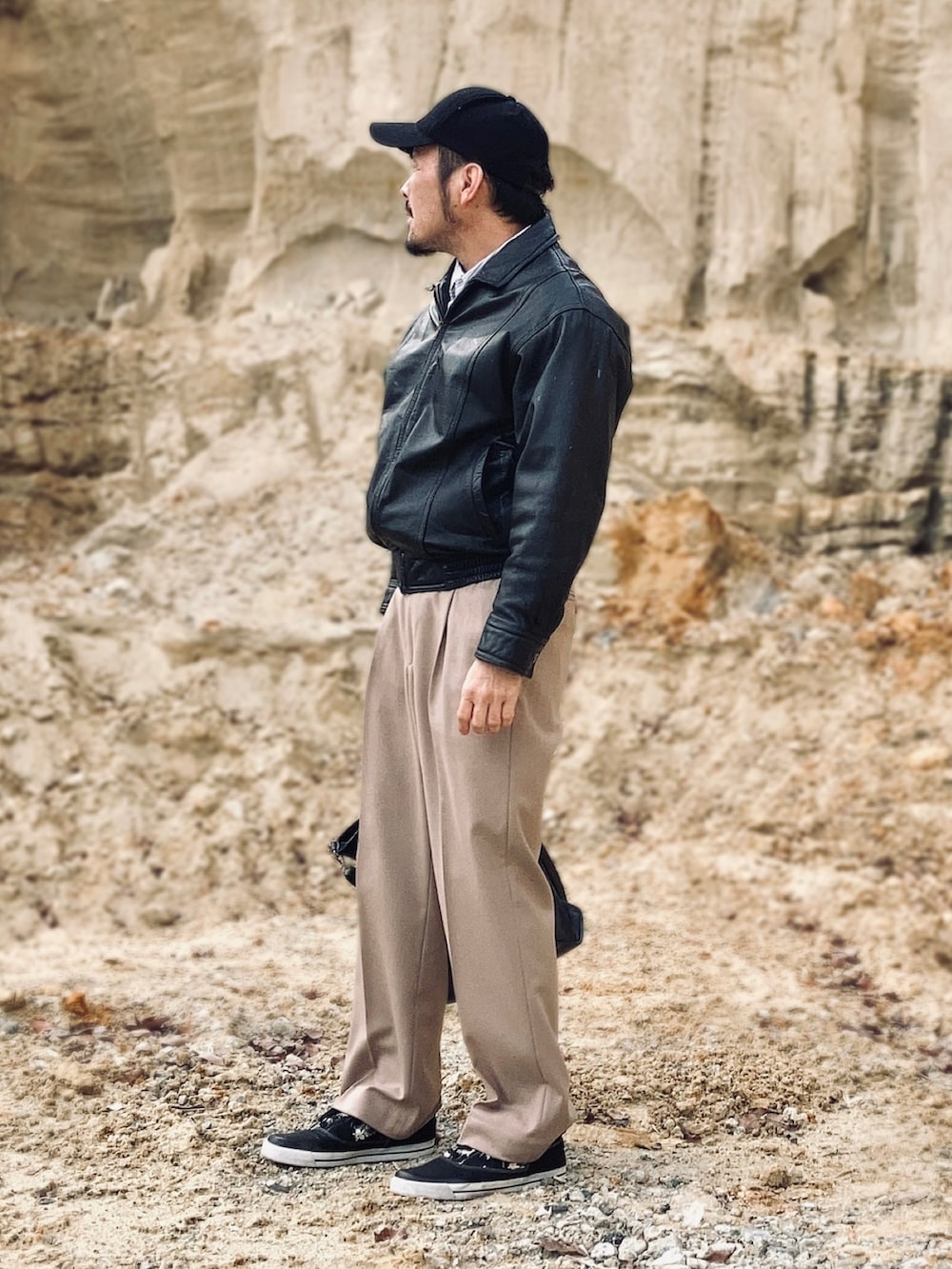 ブラック系のブルゾン、ベージュ系のスラックス、ブラック系のスニーカーを着用したメンズの春コーディネートの4枚目の写真