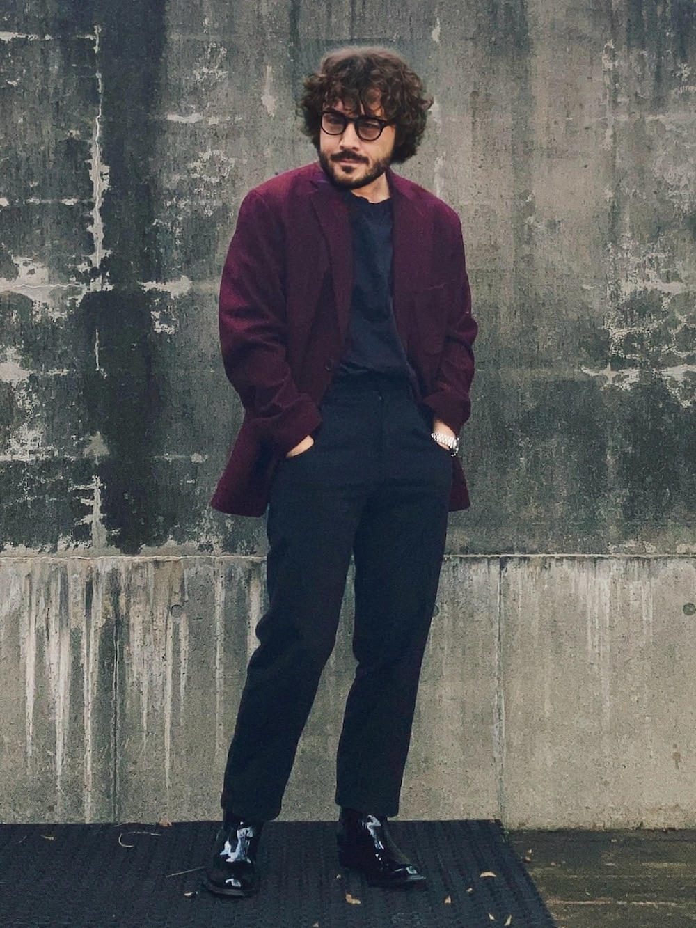 レッド系のテーラードジャケット、ブラック系のパンツ、ブラック系のブーツを着用したメンズの秋コーディネートの4枚目の写真