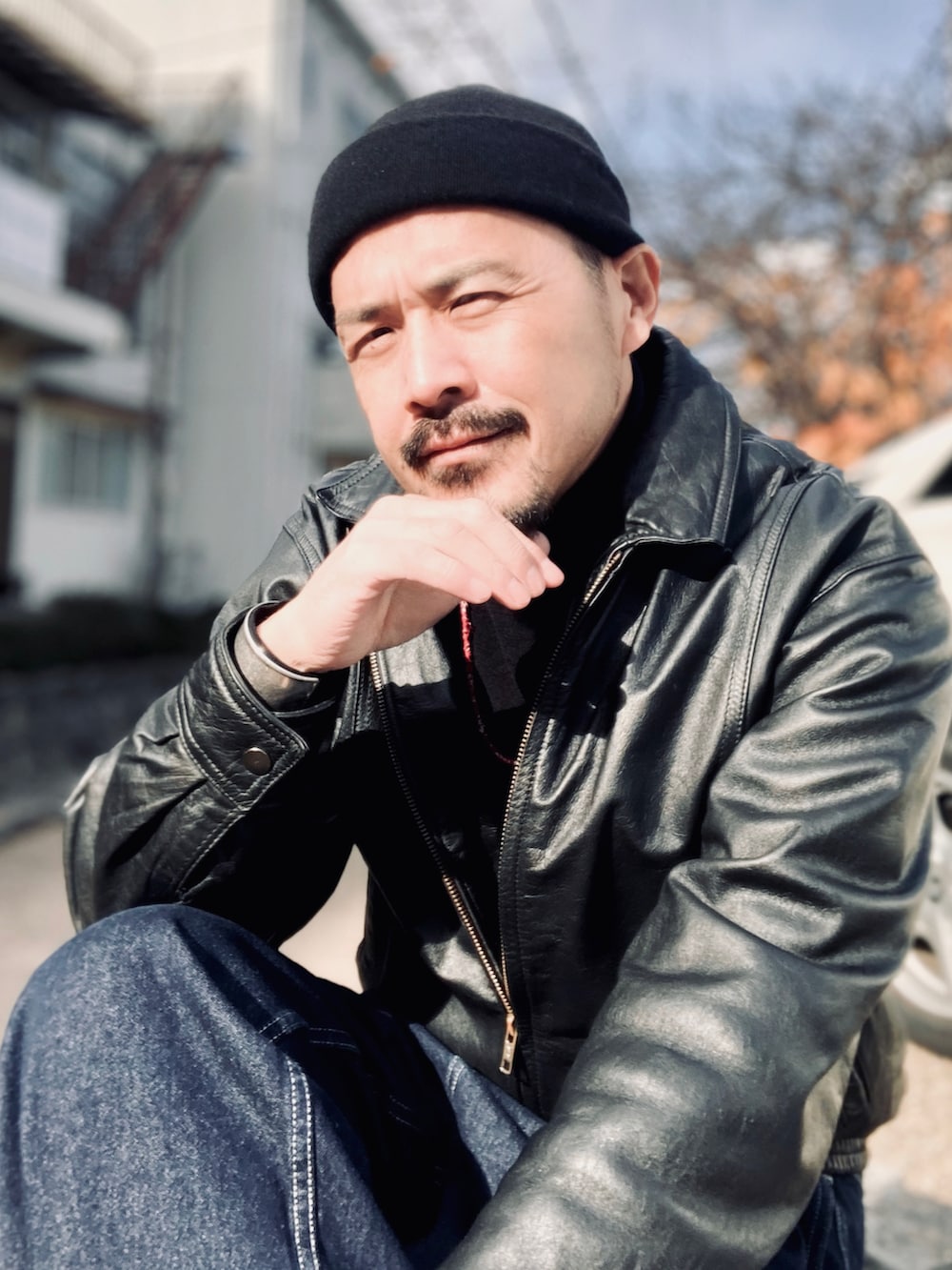 ブラック系のニット/セーター、ブラック系のブルゾン、ブルー系のデニムパンツを着用したメンズの冬コーディネートの4枚目の写真