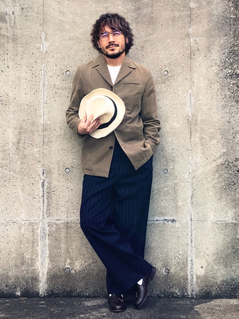 ベージュ系のテーラードジャケット、ブルー系のスラックス、ブラウン系のローファーを着用したメンズの春コーディネートの2枚目の写真