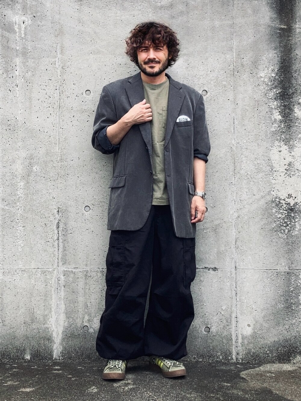 グレー系のテーラードジャケット、グリーン系のTシャツ/カットソー、ブラック系のカーゴパンツを着用したメンズの秋コーディネートの3枚目の写真