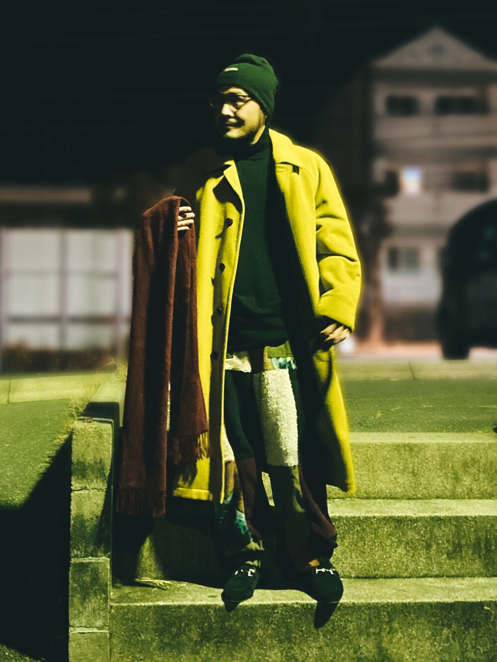 ブラック系のニット/セーター、イエロー系のステンカラーコート、その他のスウェットパンツを着用したメンズの冬コーディネートの2枚目の写真