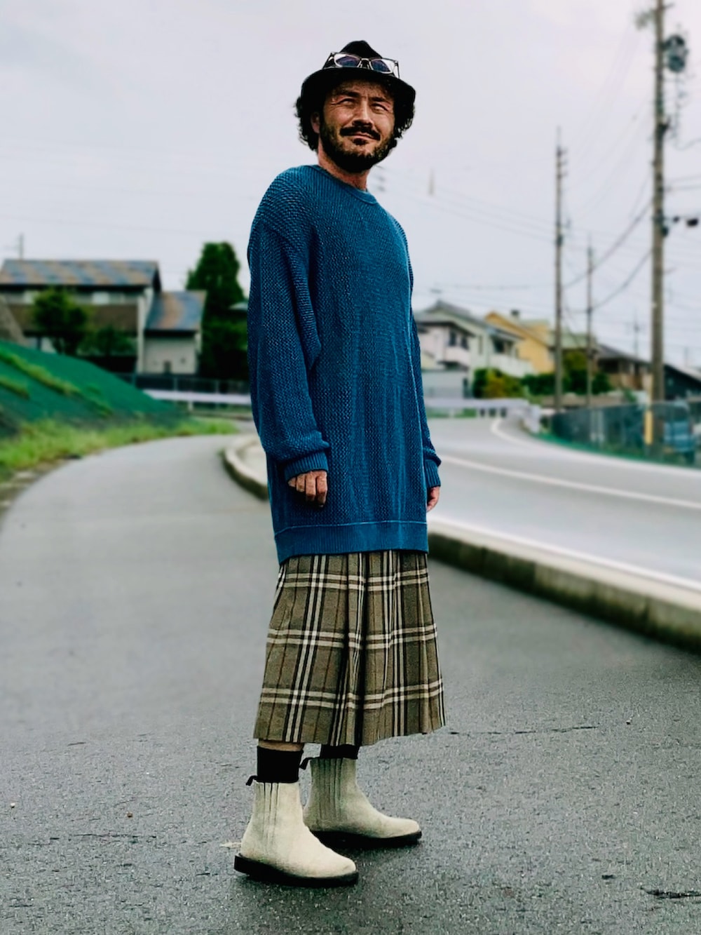 グレー系のスカート、ブルー系のニット/セーター、ベージュ系のブーツを着用したメンズの秋コーディネートの3枚目の写真