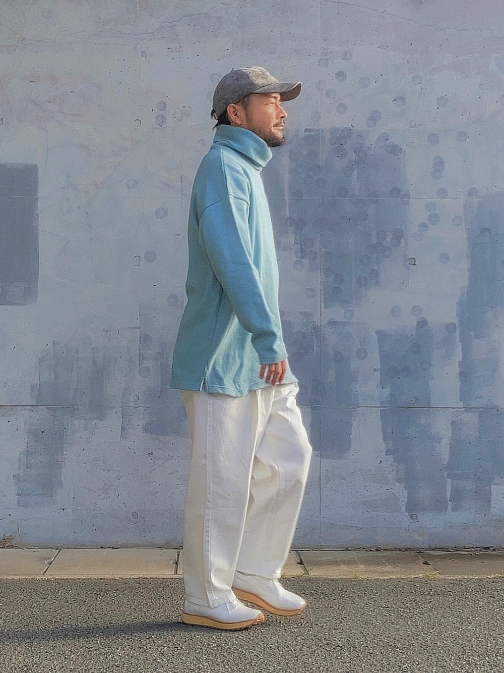 ブルー系のニット/セーター、ホワイト系のスラックス、ホワイト系のスニーカーを着用したメンズの春コーディネートの2枚目の写真