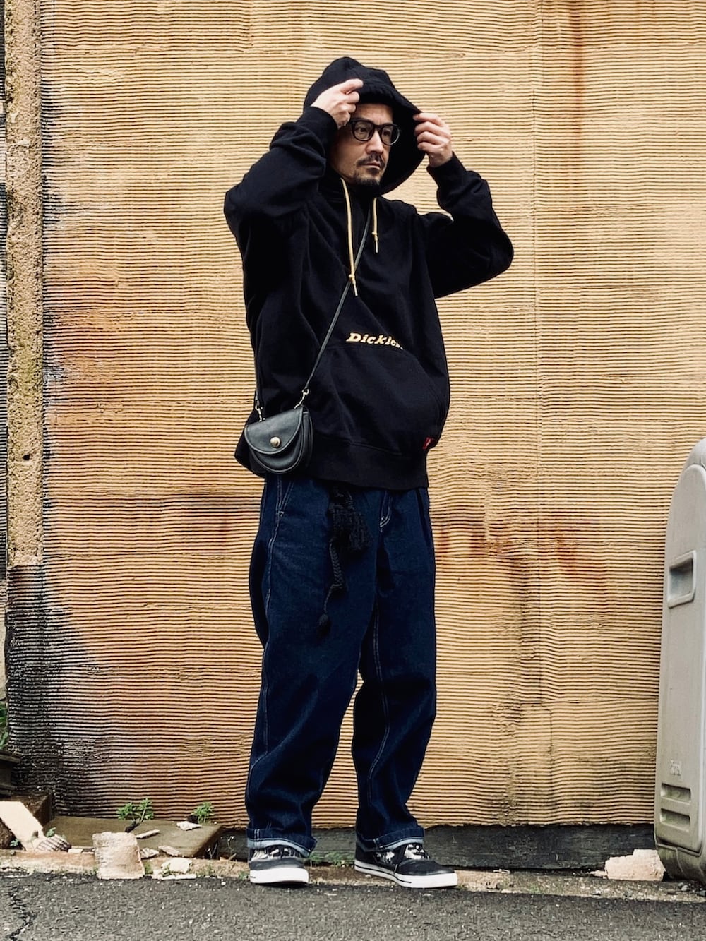 ブラック系のパーカー、ブルー系のデニムパンツ、ブラック系のスニーカーを着用したメンズの春コーディネートの3枚目の写真