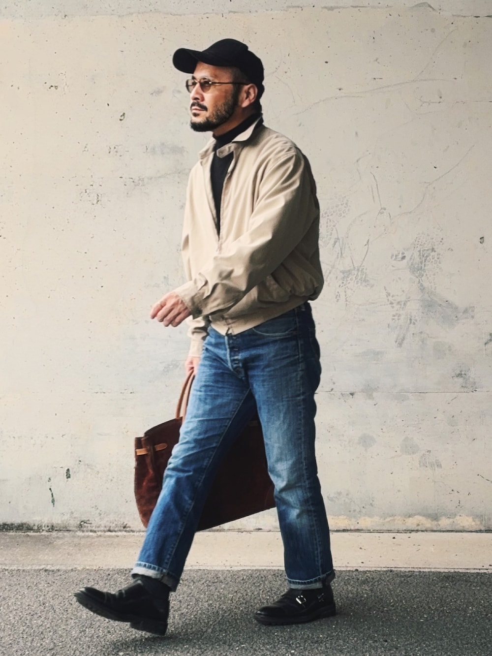 ベージュ系のブルゾン、ブルー系のデニムパンツ、ブラウン系のトートバッグを着用したメンズの冬コーディネートの3枚目の写真