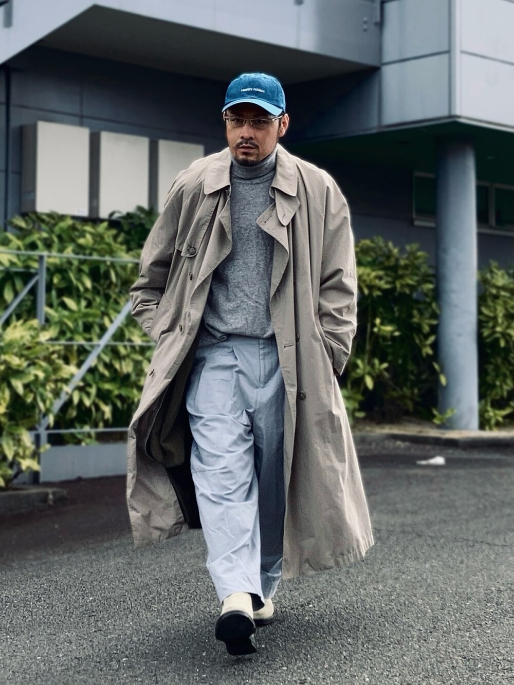 グレー系のニット/セーター、ベージュ系のトレンチコート、グレー系のパンツを着用したメンズの冬コーディネートの3枚目の写真