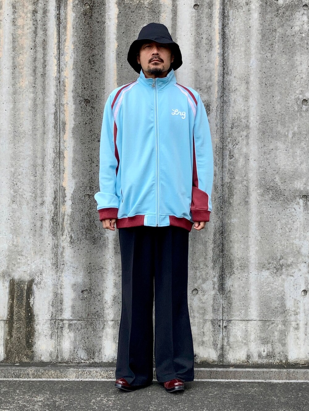 ブルー系のその他アウター、ブラック系のスラックス、レッド系のブーツを着用したメンズの秋コーディネートの2枚目の写真