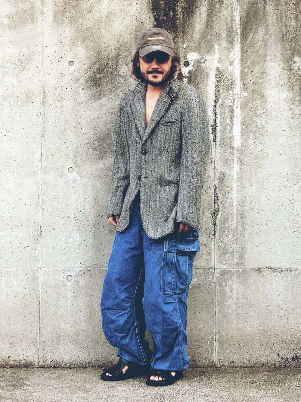 グレー系のテーラードジャケット、ブルー系のカーゴパンツ、ブラック系のサンダルを着用したメンズの秋コーディネートの2枚目の写真