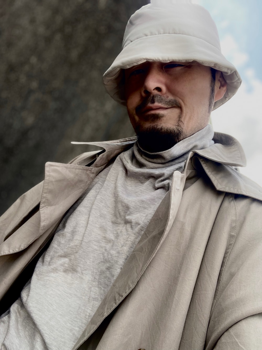 グレー系のTシャツ/カットソー、ベージュ系のトレンチコート、ブルー系のデニムパンツを着用したメンズの春コーディネートの4枚目の写真