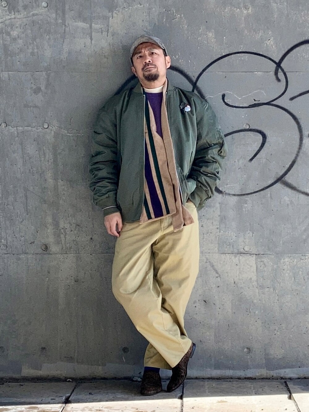 ベージュ系のTシャツ/カットソー、パープル系のスウェット、グリーン系のMA-1を着用したメンズの冬コーディネートの2枚目の写真