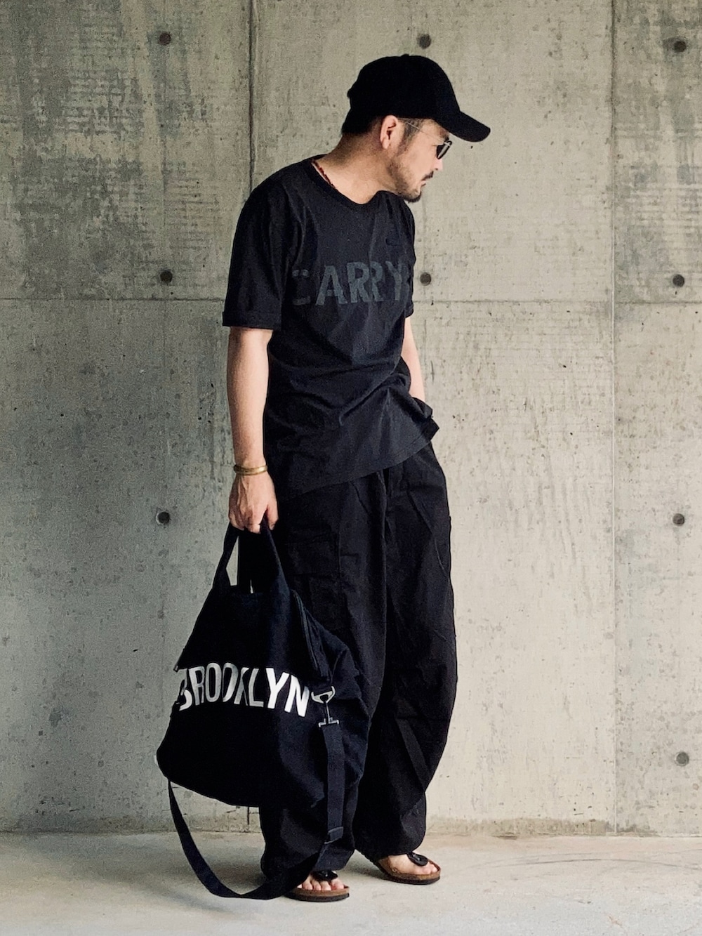 ブラック系のTシャツ/カットソー、ブラック系のカーゴパンツ、ブラック系のサンダルを着用したメンズの夏コーディネートの3枚目の写真