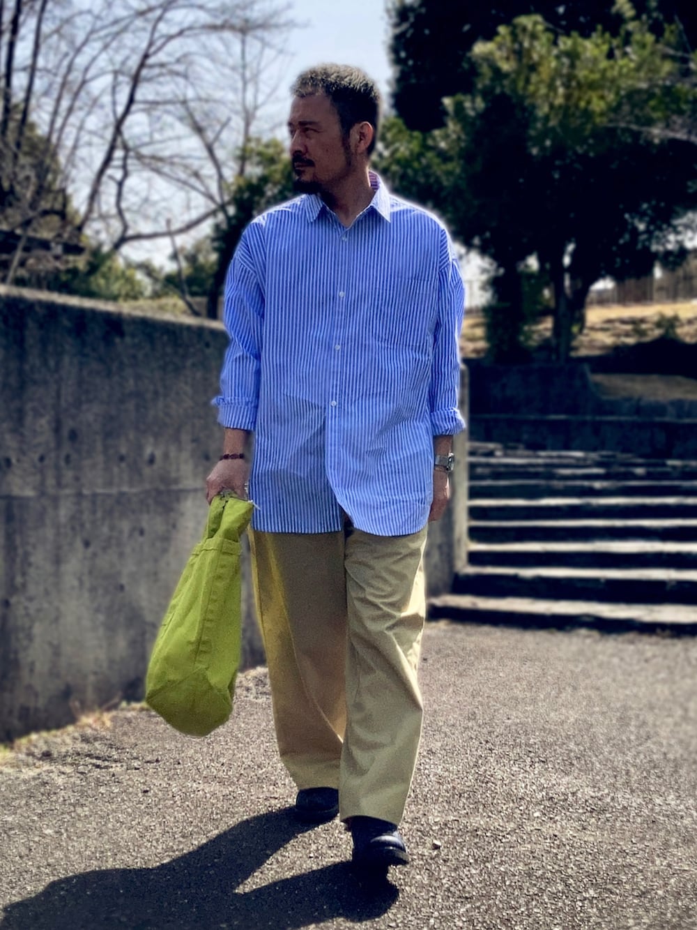 ブルー系のシャツ/ブラウス、ベージュ系のチノパンツ、ブルー系のスニーカーを着用したメンズの春コーディネートの2枚目の写真