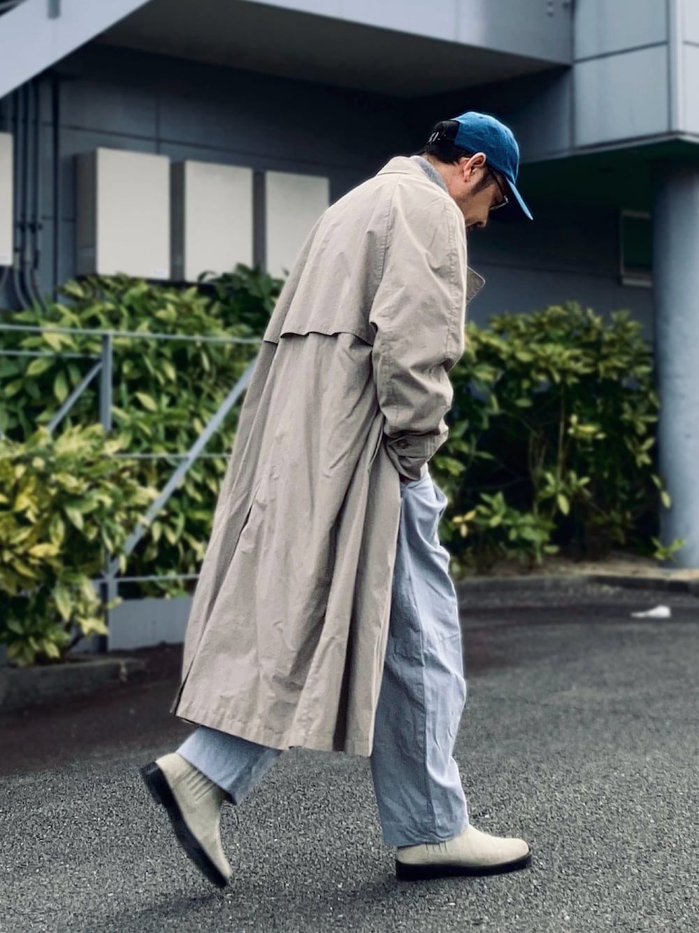 グレー系のニット/セーター、ベージュ系のトレンチコート、グレー系のパンツを着用したメンズの冬コーディネートの4枚目の写真