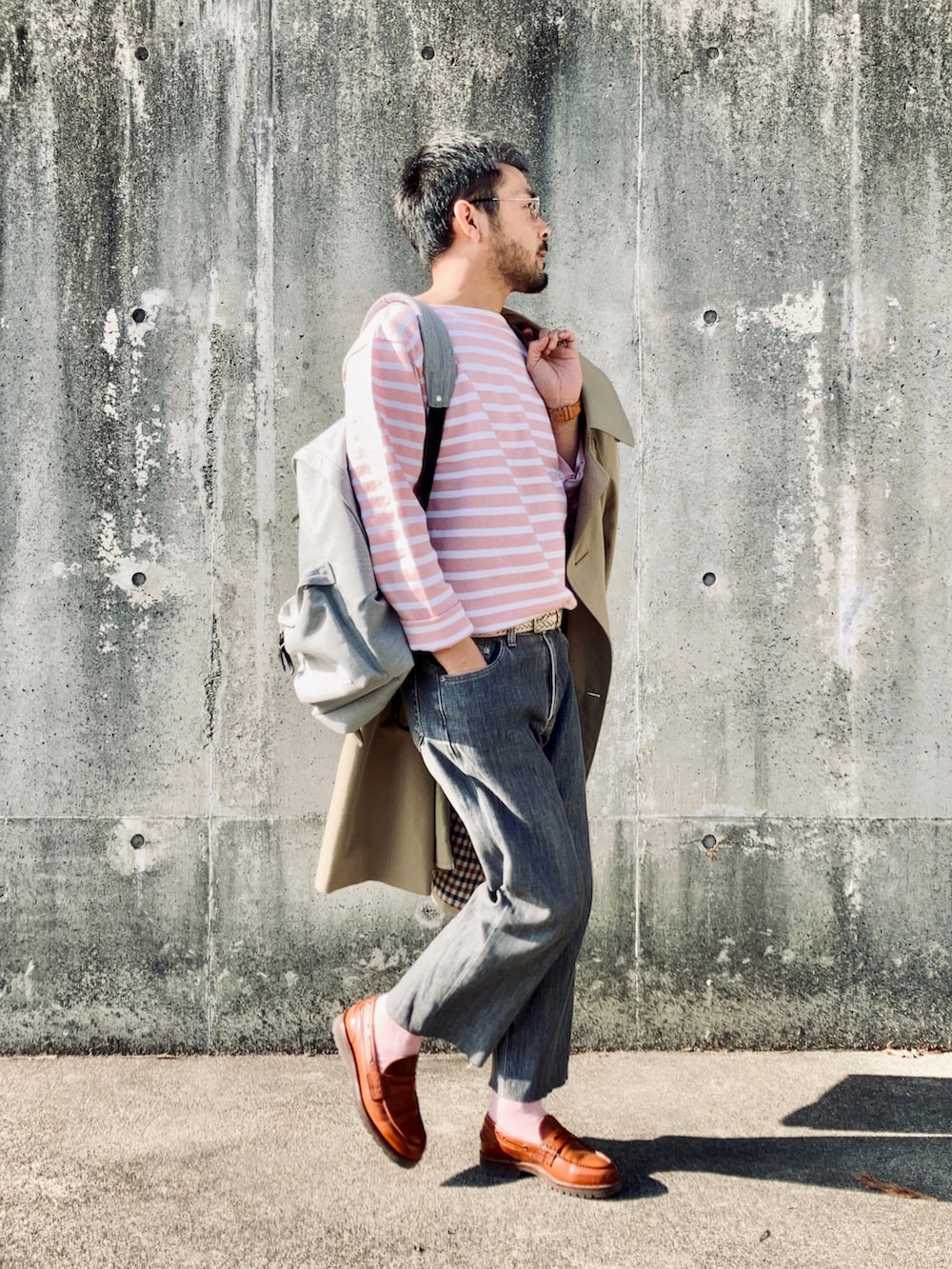 ピンク系のTシャツ/カットソー、ベージュ系のトレンチコート、グレー系のデニムパンツを着用したメンズの春コーディネートの2枚目の写真