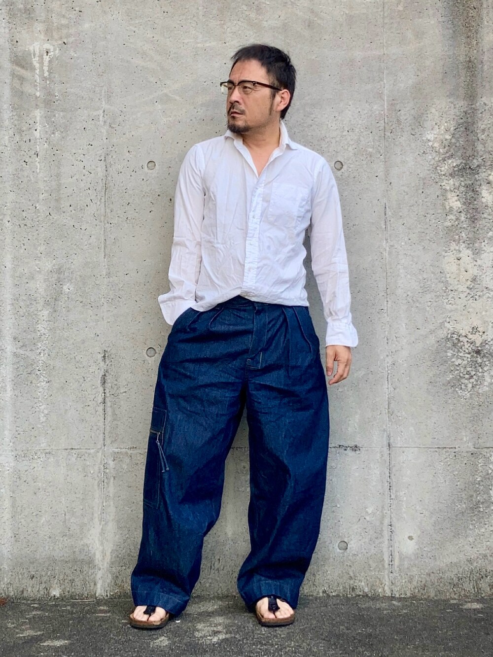 ブルー系のデニムパンツ、ホワイト系のシャツ/ブラウス、ブラック系のサンダルを着用したメンズの夏コーディネートの2枚目の写真