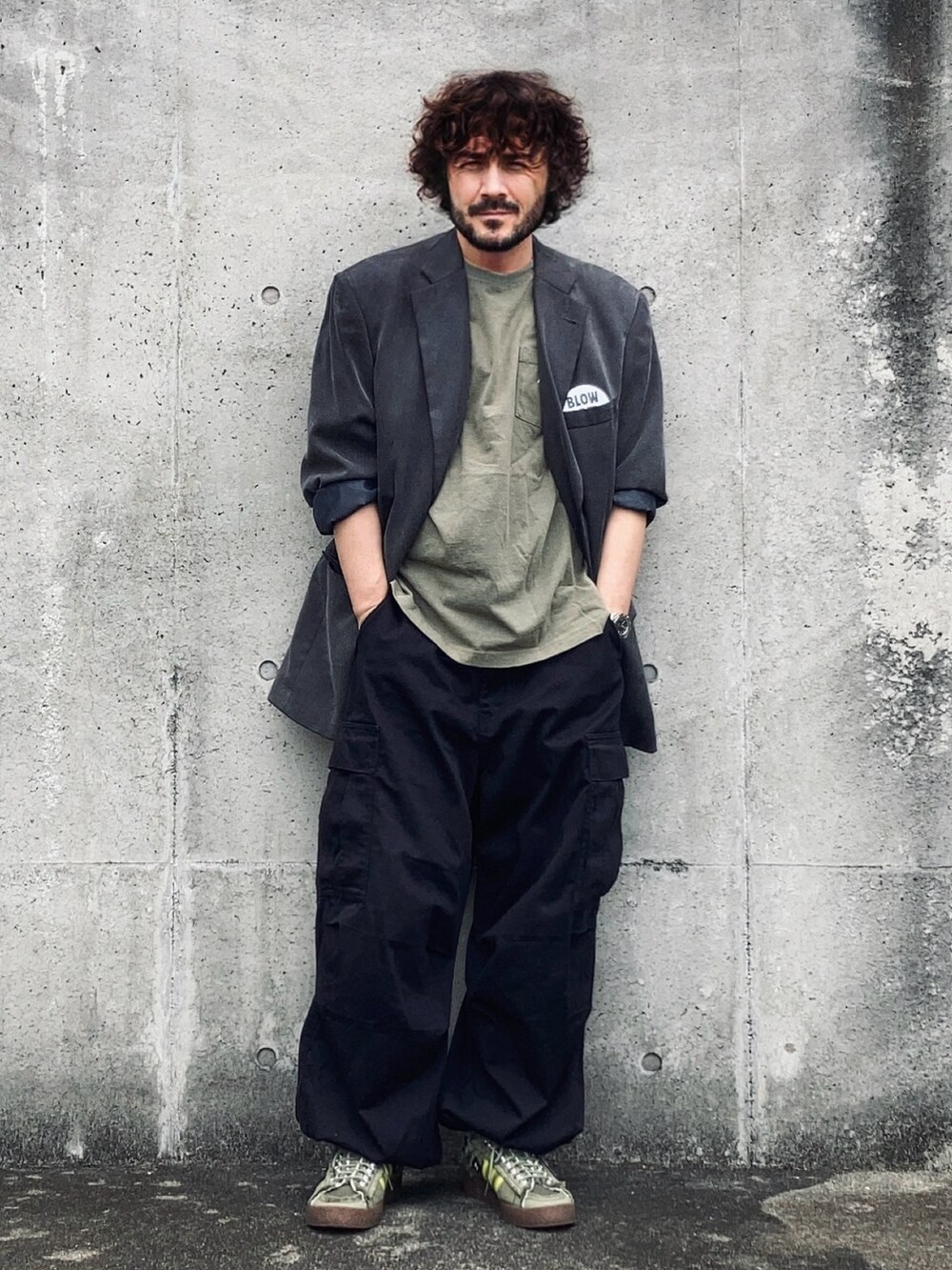 グレー系のテーラードジャケット、グリーン系のTシャツ/カットソー、ブラック系のカーゴパンツを着用したメンズの秋コーディネートの2枚目の写真