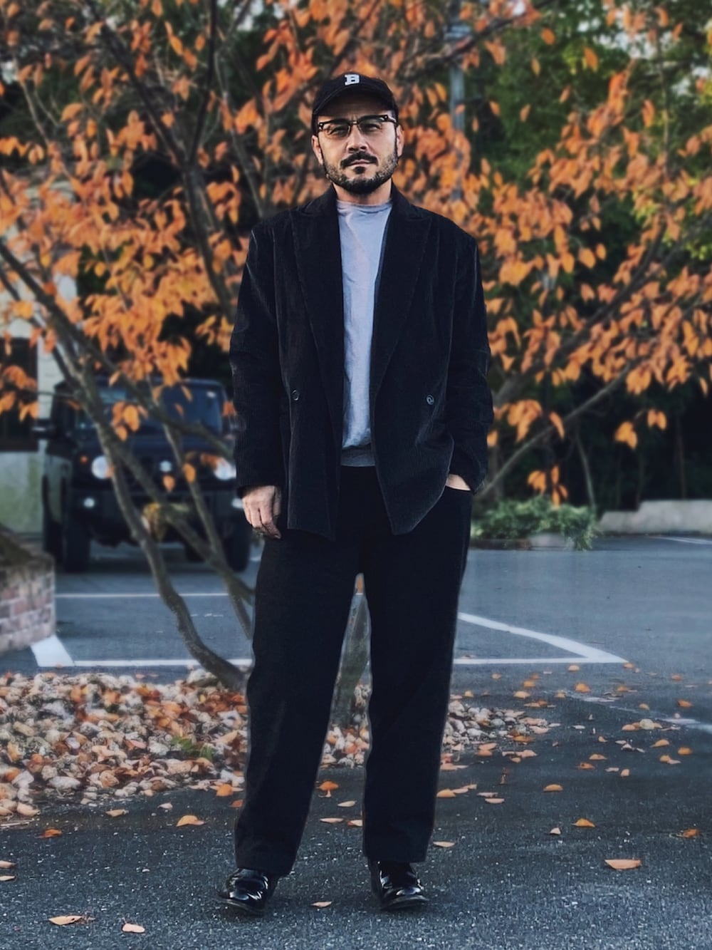 グレー系のテーラードジャケット、グレー系のスウェット、ブラック系のパンツを着用したメンズの秋コーディネートの2枚目の写真