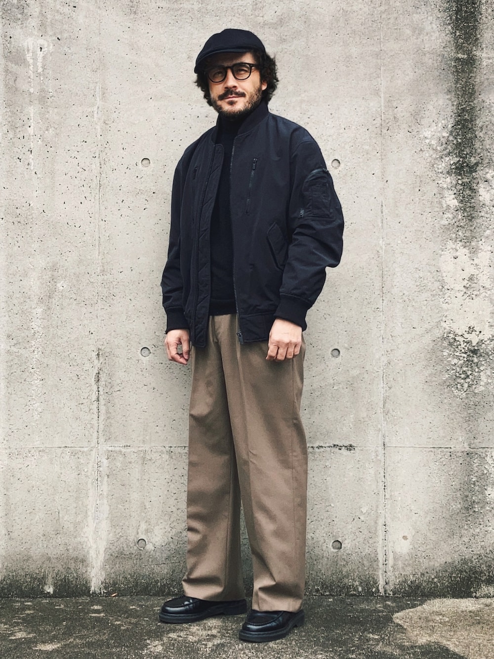 ブラック系のMA-1、ブラック系のニット/セーター、ベージュ系のスラックスを着用したメンズの春コーディネートの2枚目の写真
