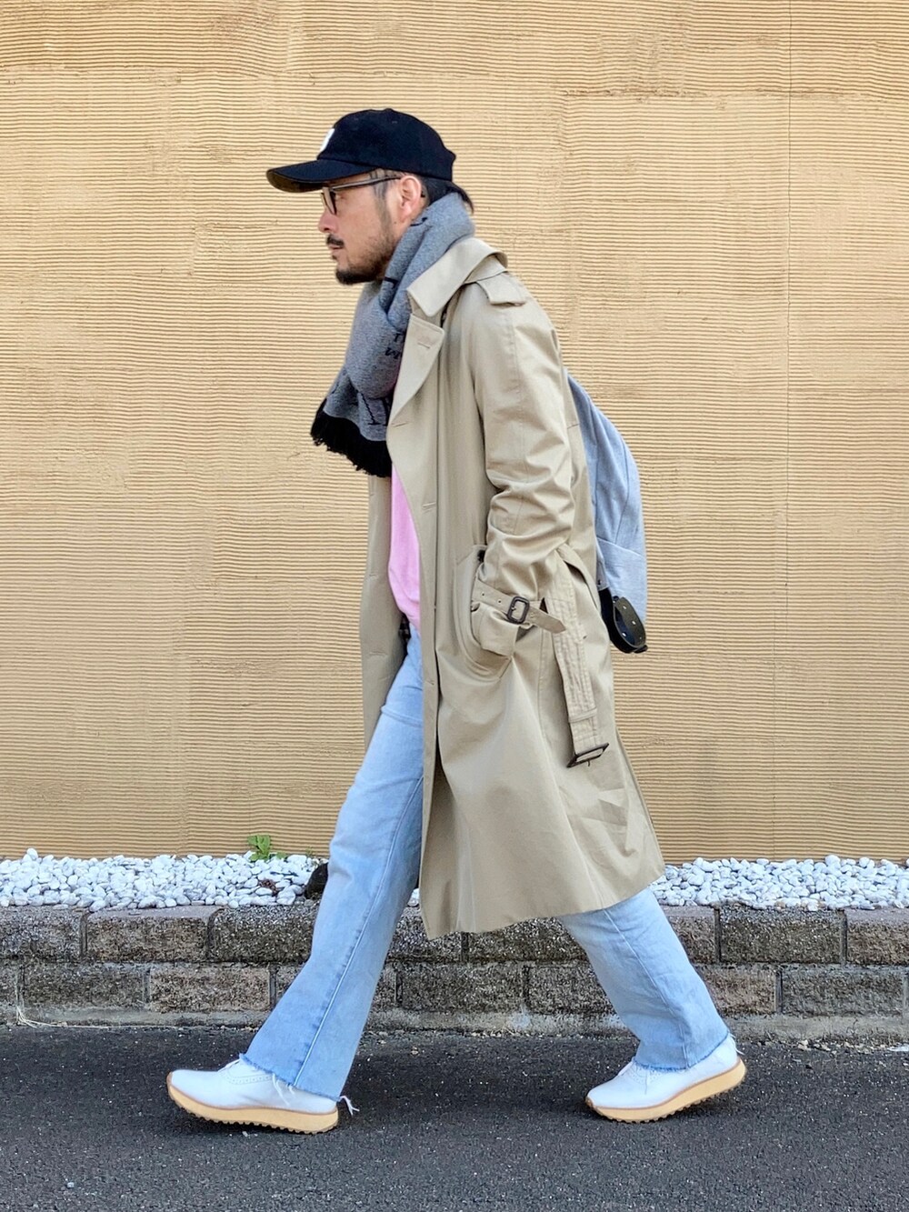ピンク系のニット/セーター、ベージュ系のトレンチコート、ブルー系のデニムパンツを着用したメンズの冬コーディネートの4枚目の写真
