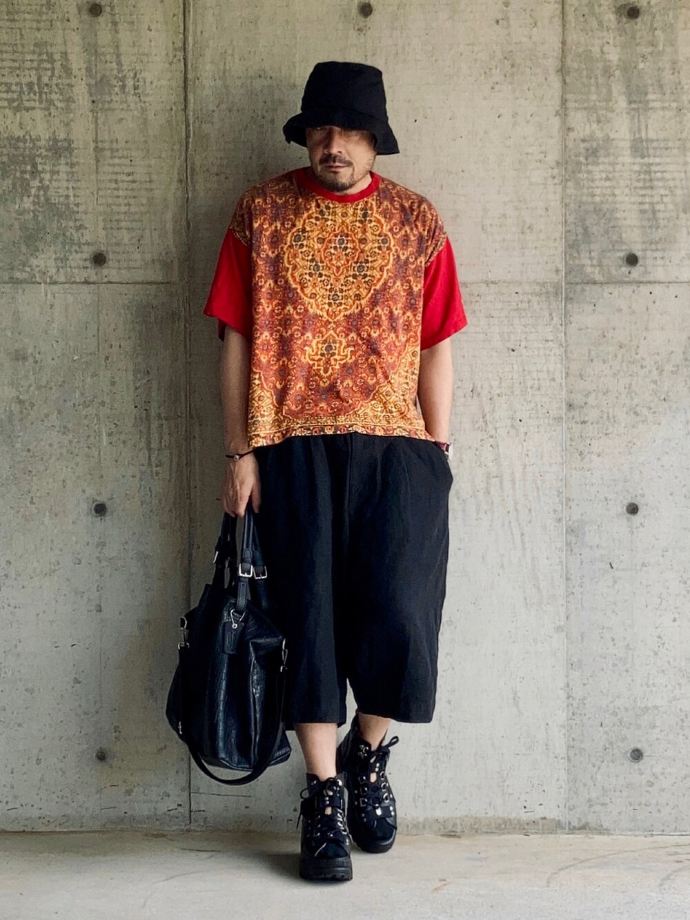 レッド系のTシャツ/カットソー、ブラック系のその他パンツ、ブラック系のサンダルを着用したメンズの夏コーディネートの3枚目の写真