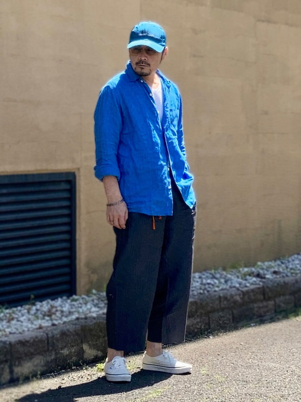 ホワイト系のTシャツ/カットソー、ブルー系のシャツ/ブラウス、グレー系のスラックスを着用したメンズの春コーディネートの3枚目の写真