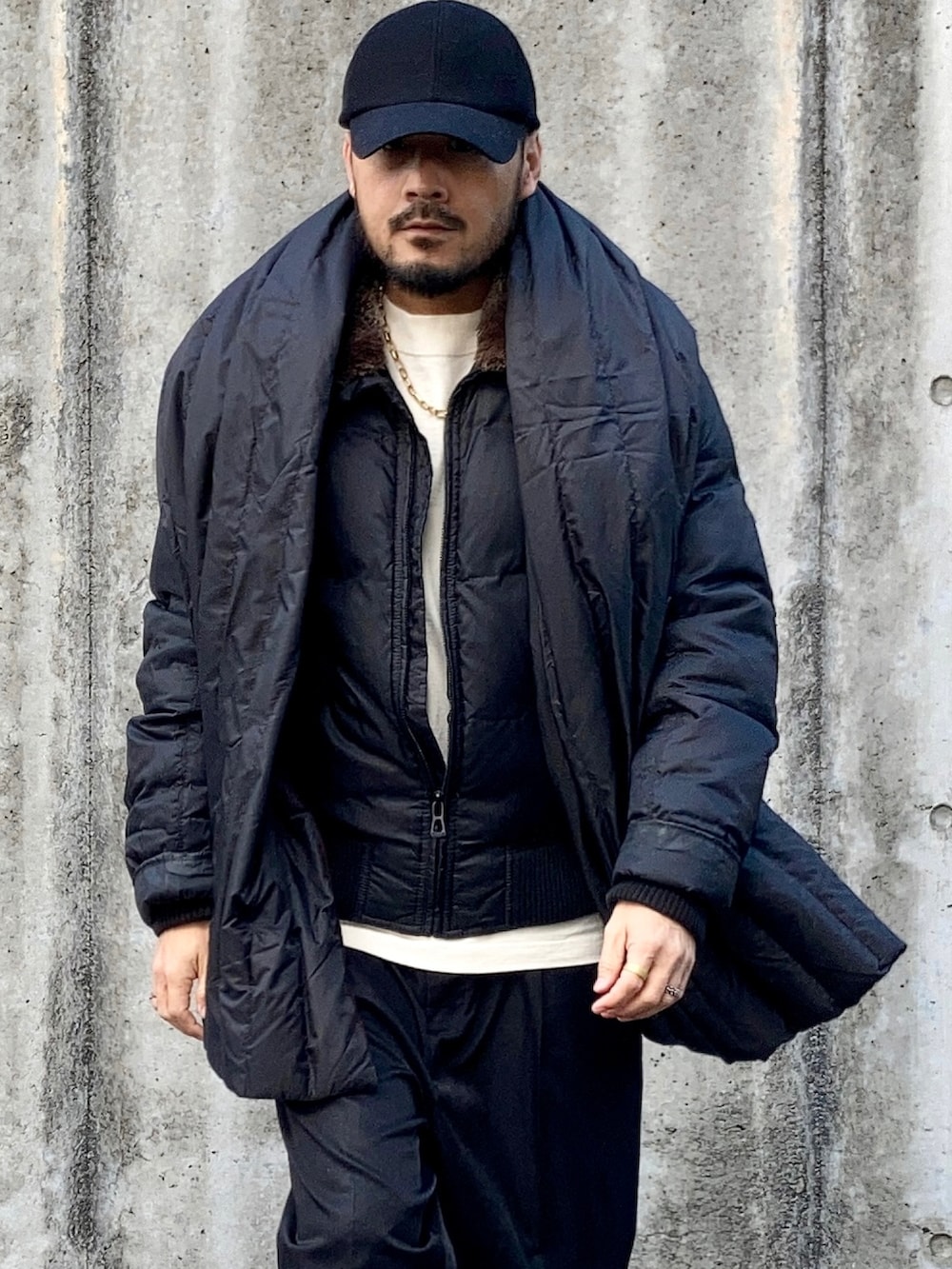 ベージュ系のTシャツ/カットソー、ブラック系のダウンジャケット/コート、ブラック系のスラックスを着用したメンズの冬コーディネートの3枚目の写真