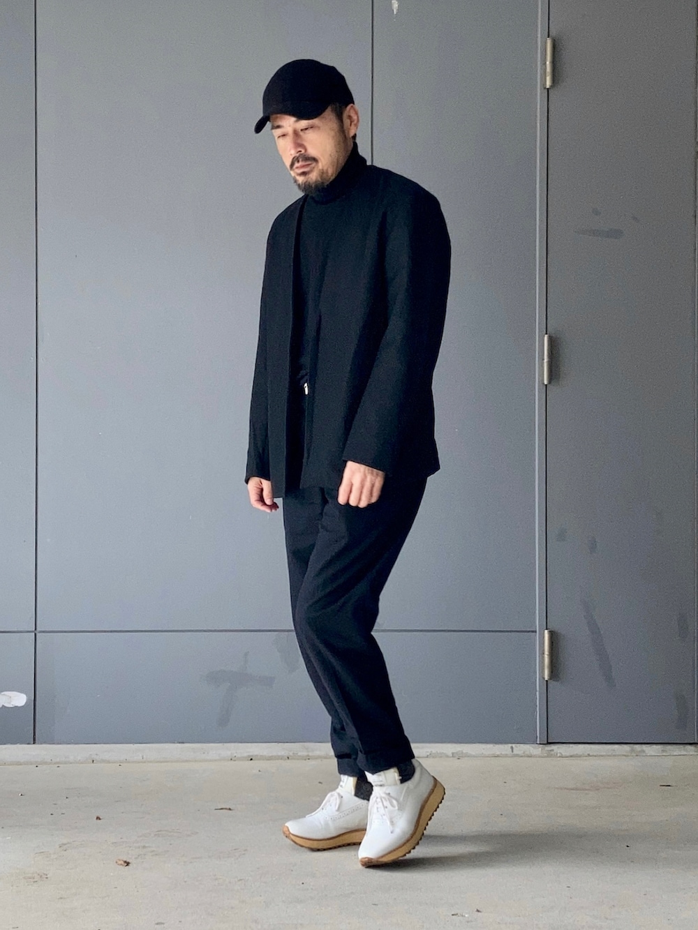 ブラック系のニット/セーター、ブラック系のスラックス、ブラック系のテーラードジャケットを着用したメンズの冬コーディネートの2枚目の写真