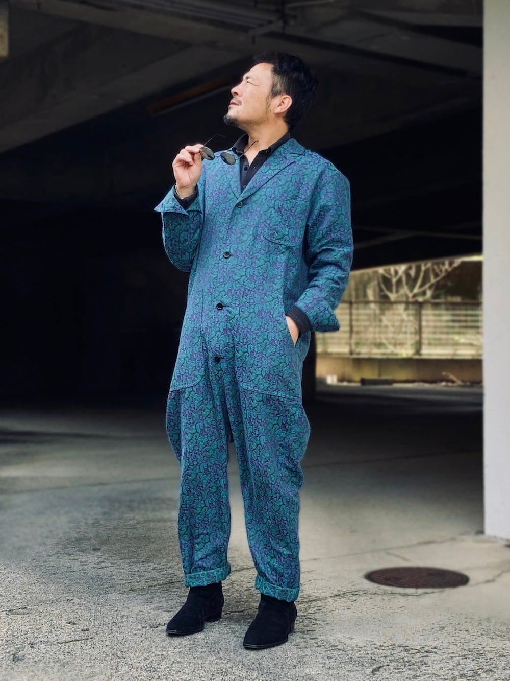 ブラック系のポロシャツ、ブルー系のつなぎ/オールインワン、ブラック系のブーツを着用したメンズの春コーディネートの2枚目の写真