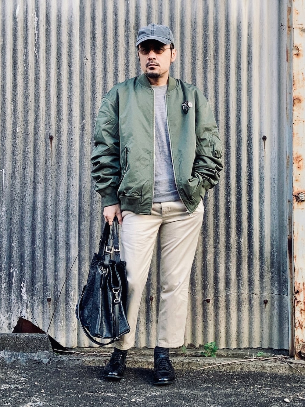 グレー系のニット/セーター、グリーン系のMA-1、ベージュ系のチノパンツを着用したメンズの秋コーディネートの4枚目の写真